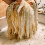 fresh pasta noodles being put into boiling water