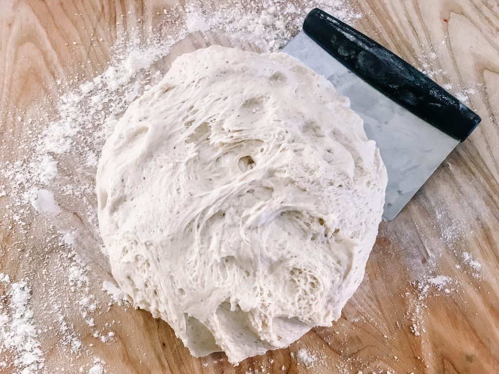 homemade sourdough sandwich rolls dough with a bench scraper