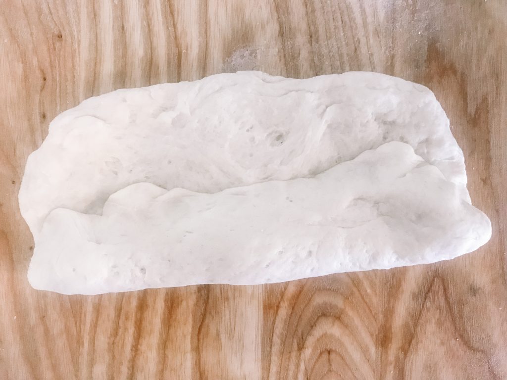 A piece of folded homemade sourdough sandwich roll dough